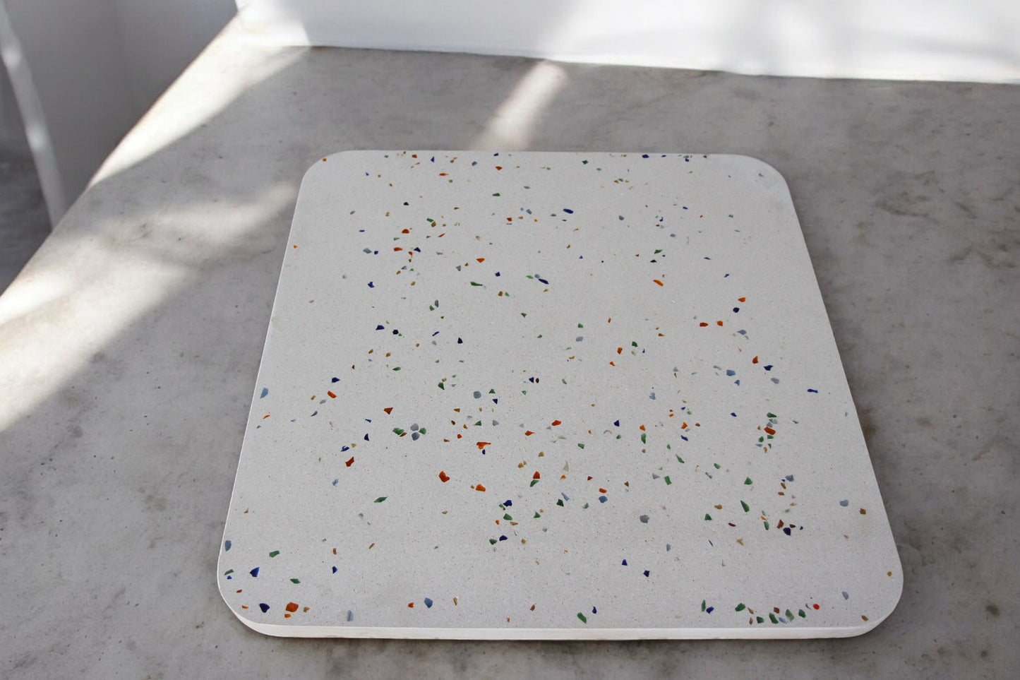 Table carrée en béton avec surface blanche et mélange de tessons de verre